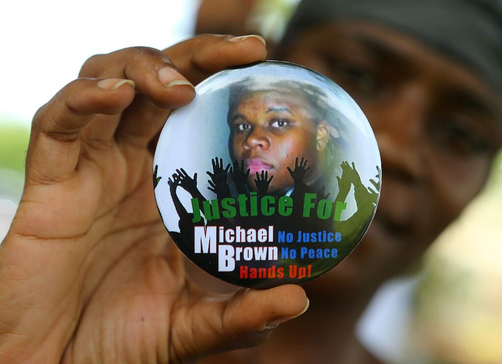 In a Thursday, Aug. 21, 2014 file photo, Nikki Jones, of Spanish Lake, Mo, holds a button in support of Michael Brown while visiting the community in the apartment development near where he was fatally shot by police in Ferguson, Mo. By almost all accounts, Brown was engaged in some sort of physical struggle with Ferguson police Officer Darren Wilson just moments before he was fatally shot. That confrontation, perhaps more than anything, may help explain why grand jurors ultimately decided not to indict Wilson for killing Brown. (AP Photo/Atlanta Journal Constitution, Curtis Compton, File)