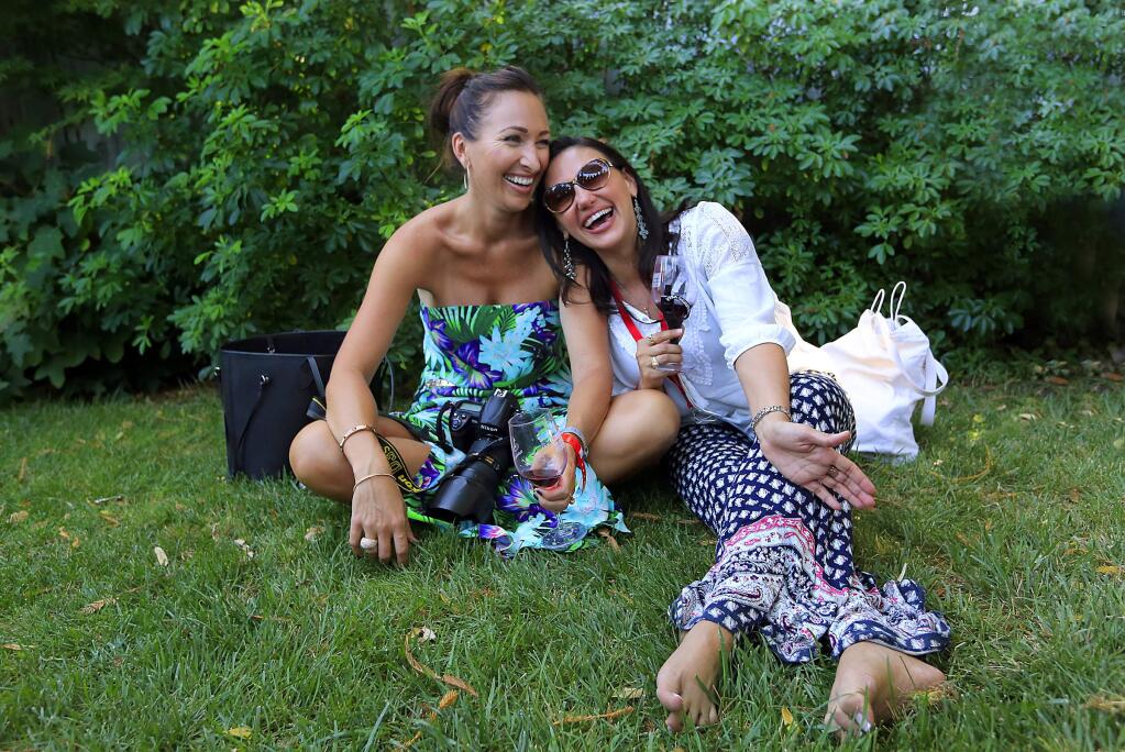 Cathy Bogaerts of Texas and Georgina Morrison of Sydney, Australia kick off their shoes and relax in the grass after a day of wine tasting at the annual Taste of Sonoma at MacMurray Ranch on Saturday, September 5, 2015. (JOHN BURGESS / The Press Democrat)