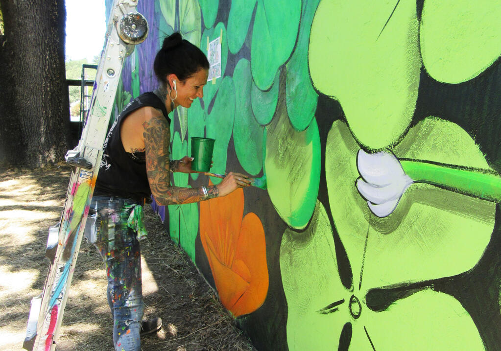 Amandalynn painting a mural on Forestville downtown building