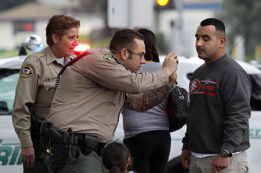 A Sonoma County Sheriff's deputy takes a photo of a stab wound to the neck of a man, known only as Daniel, who tried to intervene in a robbery on Sebastopol Rd. in Santa Rosa on Saturday, January 17, 2015. (photo by John Burgess/The Press Democrat)