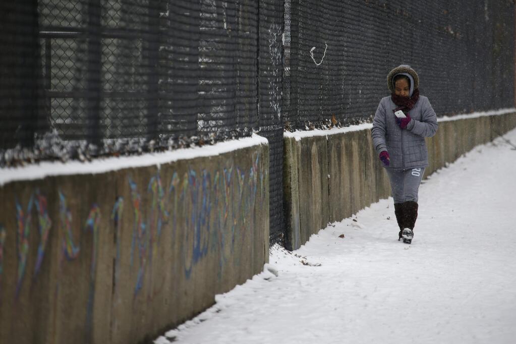 A woman walks through the snow during a winter storm, Tuesday, Jan. 6, 2015, in Philadelphia. Snow slowed commuter rail and air travel in the Philadelphia area. (AP Photo/Matt Slocum)