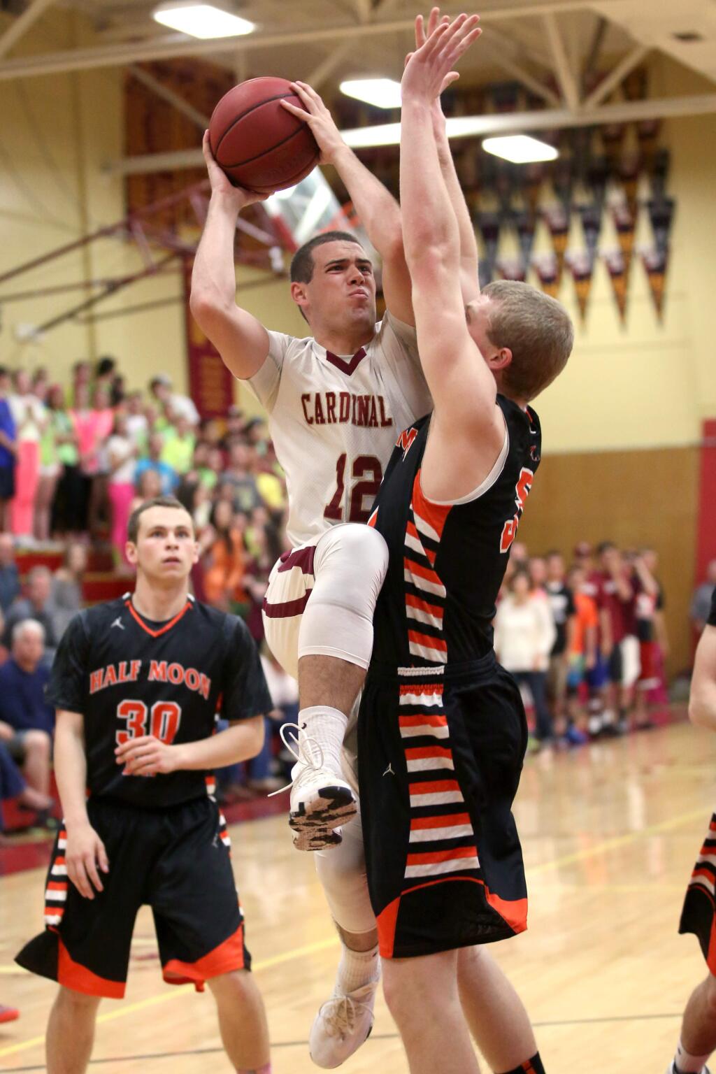 Cardinal Newman's Connor Rubattino goes to the basket as Half Moon Bay's Austin Hilton defends during the game held at Cardinal Newman High School, Saturday, March 14, 2015. (CRISTA JEREMIASON / The Press Democrat)