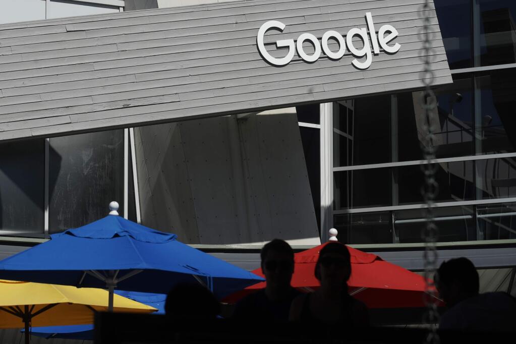 FILE - In this Sept. 24, 2019, file photo people walk by a Google sign on the campus in Mountain View, Calif. Alphabet's board of directors is investigating claims of sexual misconduct made against executives and how the company handled the allegations. (AP Photo/Jeff Chiu, File)