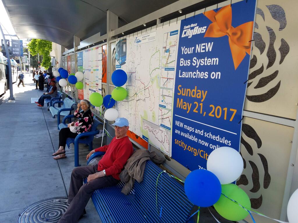 Passengers near a sign announcing new Santa Rosa CityBus routes at the Santa Rosa Transit Mall. (KEVIN MCCALLUM/ PD)