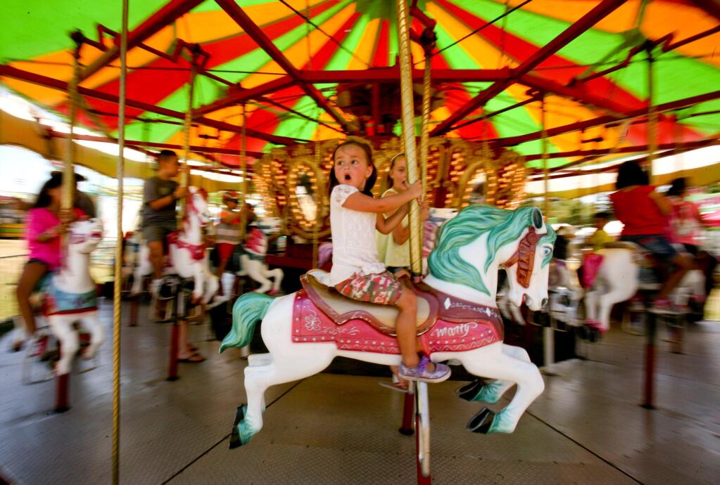 Rubie Madkovich, 4, of Petaluma, looks around in wonder as she rides the merry-go-round on opening day at the Sonoma-Marin Fair Wednesday, June 24, 2015. (SCOTT MANCHESTER/ARGUS-COURIER STAFF)