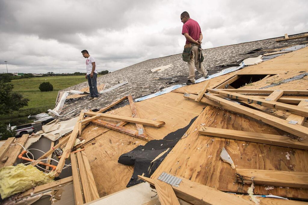 Edgar Mascorro, left, and Emir Nevarez check out the damage on the rooftop at the Silver Springs Apartments in North Austin, Texas, Sunday, May 24, 2015. Record rainfall was wreaking havoc across a swath of the U.S. Midwest on Sunday, causing flash floods in normally dry riverbeds, spawning tornadoes and forcing at least 2,000 people to flee. (Ricardo B. Brazziell/Austin American-Statesman via AP) AUSTIN CHRONICLE OUT, COMMUNITY IMPACT OUT, INTERNET AND TV MUST CREDIT PHOTOGRAPHER AND STATESMAN.COM, MAGS OUT