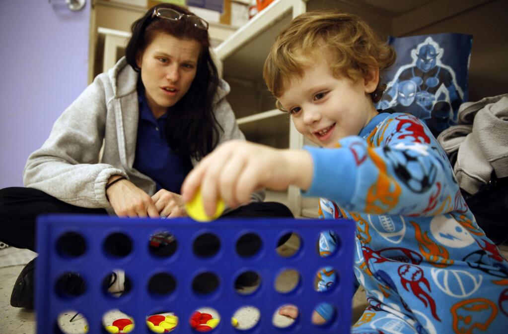 Clara Martin and her son Nicodemus Sullivan, 3, play the game Connect Four before a Christmas party at Catholic Charities Family Support Center in Santa Rosa, California on Tuesday, December 23, 2014. (BETH SCHLANKER/ The Press Democrat)