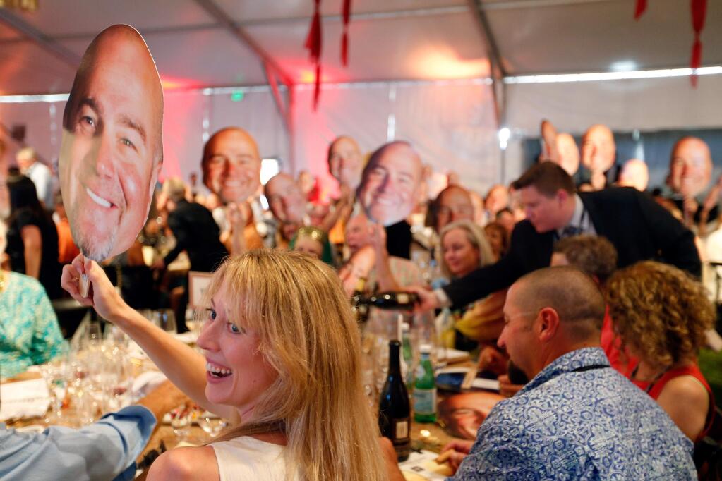 Paten Hughes, left, and other guests hold up the face of honorary event chair Dan Kosta to playfully draw attention to the Kosta Browne wine lot up for auction during the Sonoma Harvest Wine Auction at Chateau St. Jean in Kenwood, California on Sunday, September 4, 2016. (Alvin Jornada / The Press Democrat)