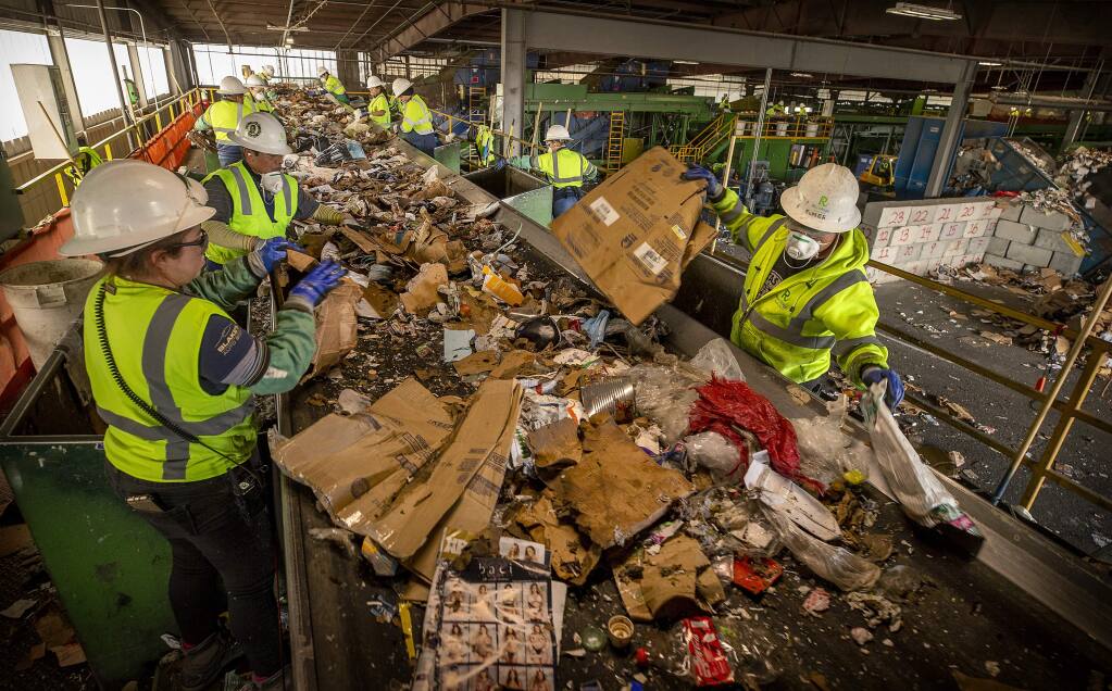 Workers separate cardboard from single stream home recycling cans at Recology Sonoma Marin in Santa Rosa on Monday. The sorters are finding dozens of hypodermic needles daily among the can, bottles and paper goods. (photo by John Burgess/The Press Democrat)