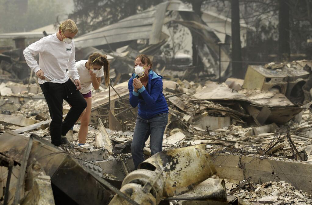 Mary Caughey, center in blue, reacts with her son Harrison, left, after finding her wedding ring in debris at her home destroyed by fires in Kenwood, Calif., Tuesday, Oct. 10, 2017. (AP Photo/Jeff Chiu)