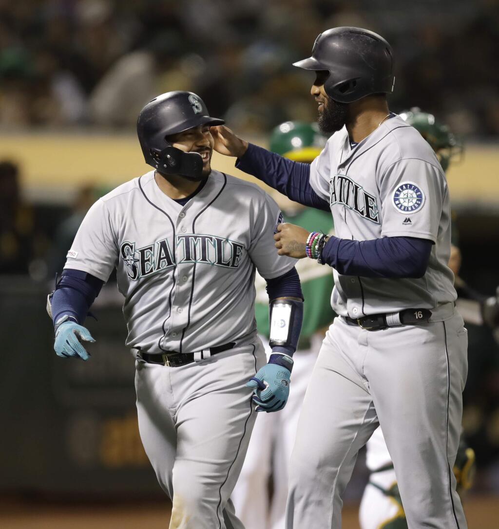 The Seattle Mariners' Omar Narvaez, left, celebrates with Domingo Santana after hitting a two-run home run off the Oakland Athletics' Wei-Chung Wang during the seventh inning, Friday, June 14, 2019, in Oakland. (AP Photo/Ben Margot)