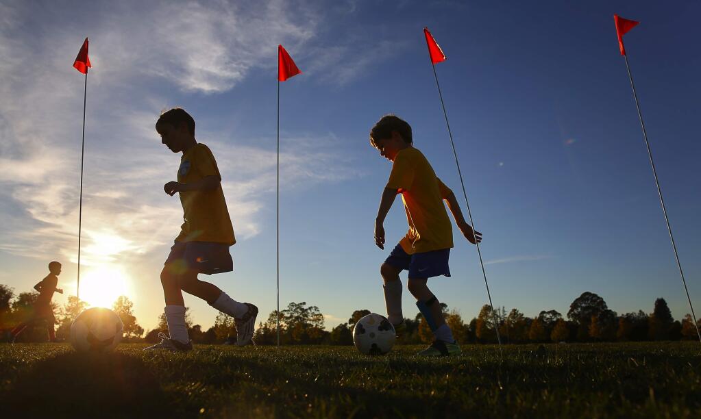 Evan Grafe, left, and Micah Hoese, both 8, weave their way around flags during their SRU Cosmos U9 soccer practice at A Place to Play park, in Santa Rosa, on Thursday, November 12, 2015. (Christopher Chung/ The Press Democrat)