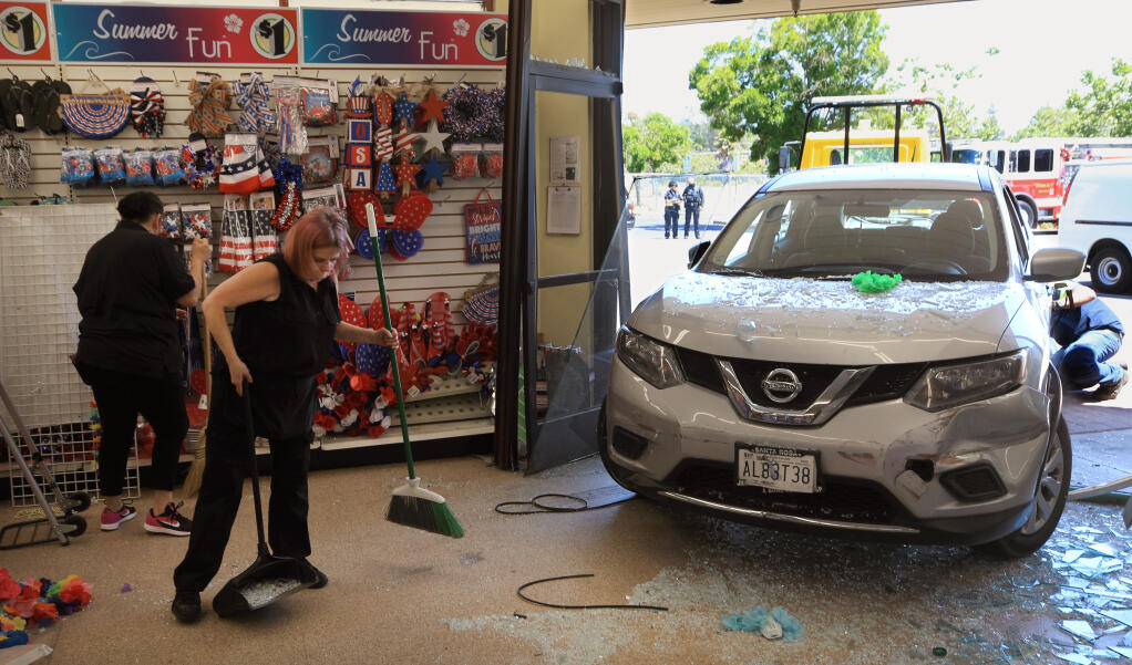 Dollar Tree employees Kari Mackie and Clara Alvarez, left, clean up after a driver plowed in to the store on Industrial Drive in Santa Rosa, Monday, May 31, 2021. There was an injury to a customer at the store.  (Kent Porter / The Press Democrat) 2021