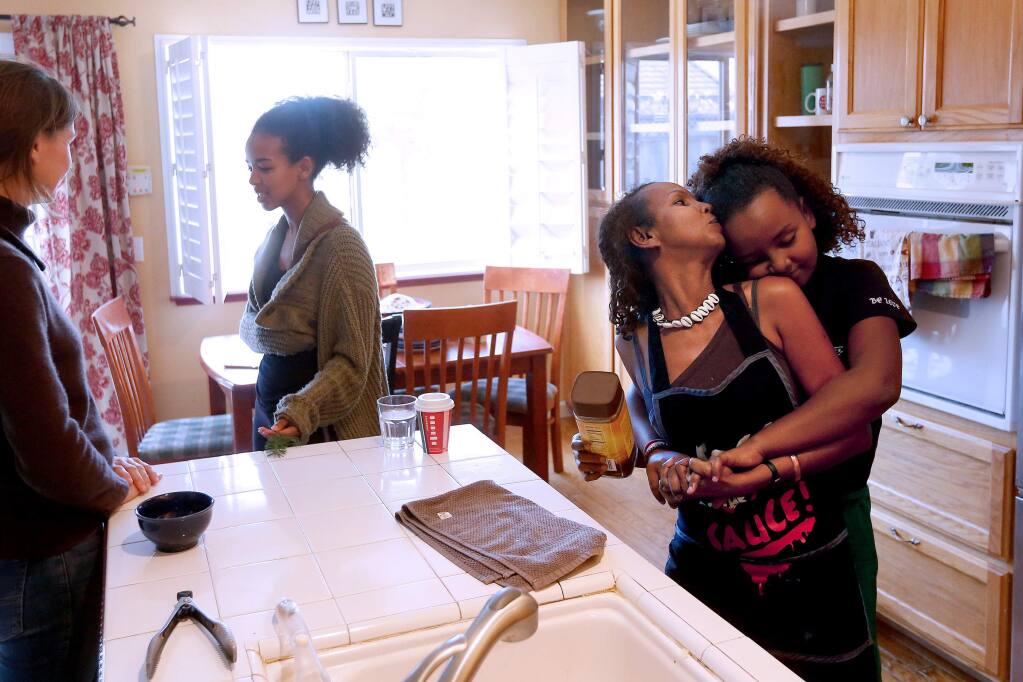 Shugri Salh turns to kiss her daughter Sabina, 11, while they prepare lunch for friends at their home in Rohnert Park, California, on Wednesday, December 26, 2018. (Alvin Jornada / The Press Democrat)