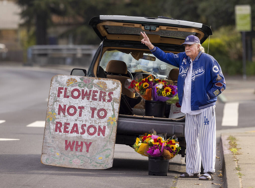 Michael Larrain left a Hollywood career in his mid-20s to try his hand at writing. Larrain has been selling his “Flowers Not to Reason Why” from the back of his car on East Cotati Avenue for nearly 50 years. (John Burgess/The Press Democrat)
