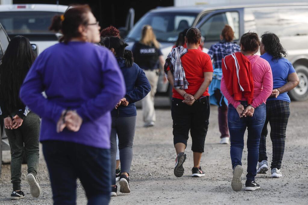 Government agents lead suspects in custody towards a restroom during an immigration sting at Corso's Flower and Garden Center, Tuesday, June 5, 2018, in Castalia, Ohio. The operation is one of the largest against employers in recent years on allegations of violating immigration laws. (AP Photo/John Minchillo)