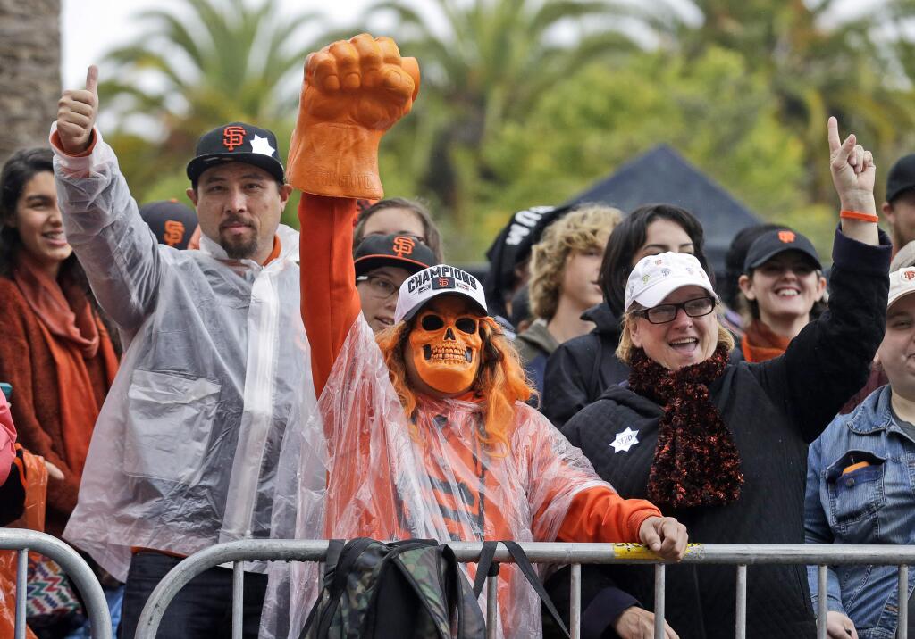 San Francisco Giants fans wait in the rain for the start of the victory parade for the 2014 baseball World Series Champion San Francisco Giants on Friday, Oct. 31, 2014 in San Francisco. (AP Photo/Jeff Chiu)