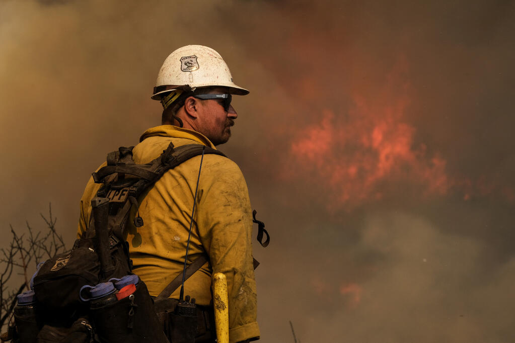 A firefighter watches as a wildfire burns Wednesday, Oct. 13, 2021, in Goleta, Calif. A wildfire raging through Southern California coastal mountains threatened ranches and rural homes and kept a major highway shut down Wednesday as the fire-scarred state faced a new round of dry winds that raise risk of flames. The Alisal Fire covered more than 22 square miles (57 square kilometers) in the Santa Ynez Mountains west of Santa Barbara. (AP Photo/Ringo H.W. Chiu)
