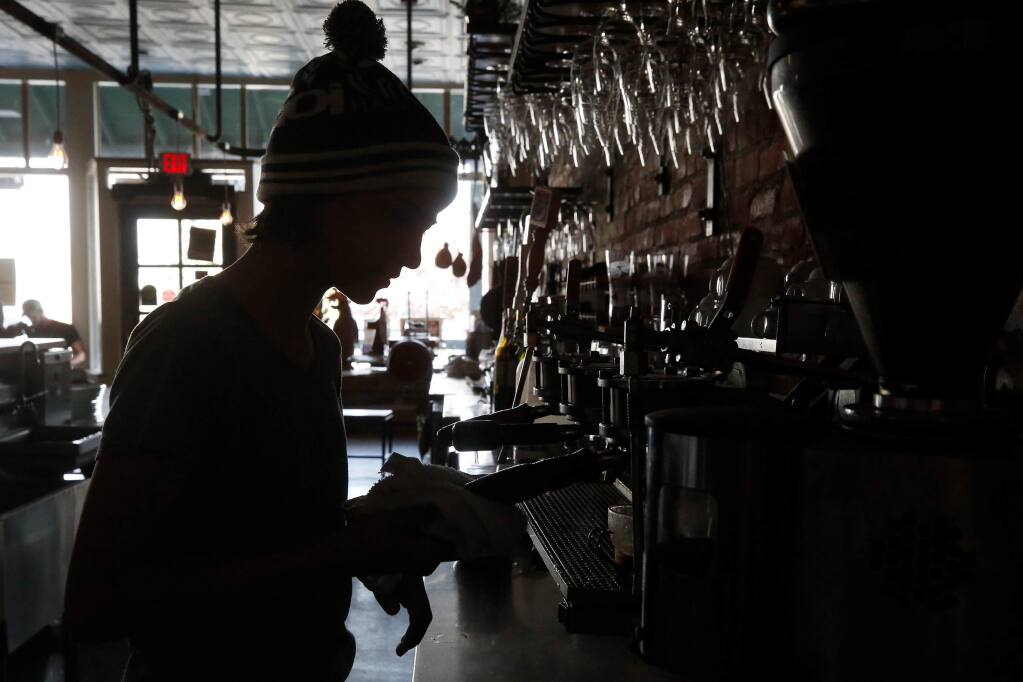Dalia Bugica, 11, makes cappuccino for local residents at the bar in Diavola Pizzeria which remains darkened due to power outages and the Kincade Fire, in Geyserville, California, on Wednesday, October 30, 2019. The widespread loss of power because of PG&E shut-offs during the Kincade fire affected the reliability of cellphone networks. (Alvin Jornada / The Press Democrat)