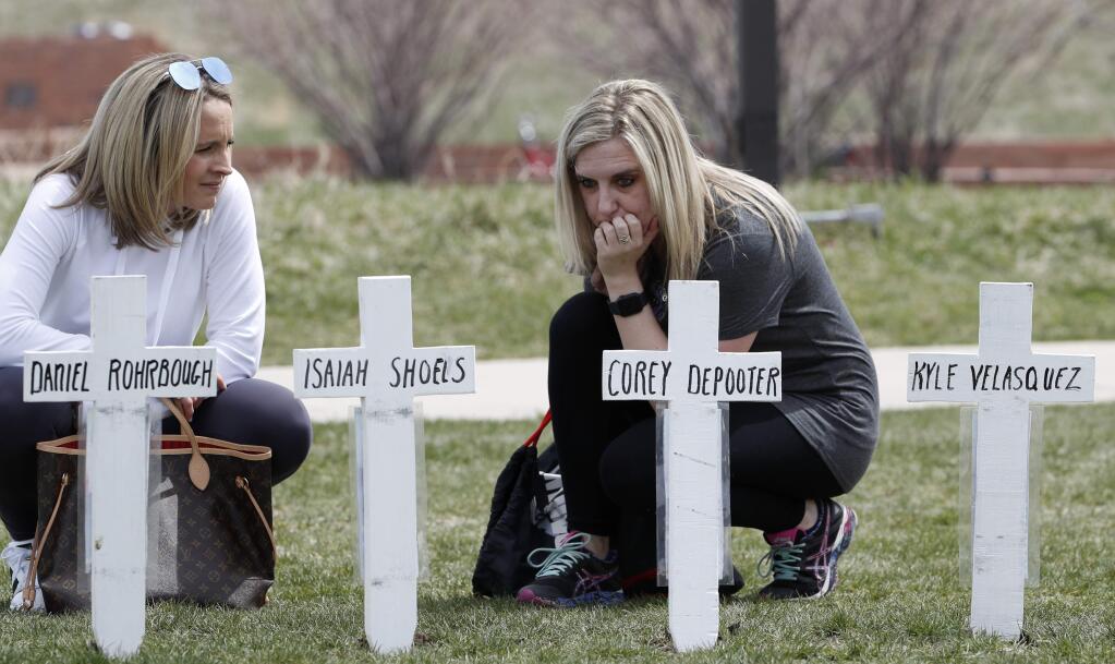 Cassandra Sandusky, right, a graduate of Columbine High School, pauses with her friend, Jennifer Dunmore, at a row of crosses bearing the names of the victims of the attack at the school 20 years ago before a program for the victims Saturday, April 20, 2019, in Littleton, Colo. (AP Photo/David Zalubowski)