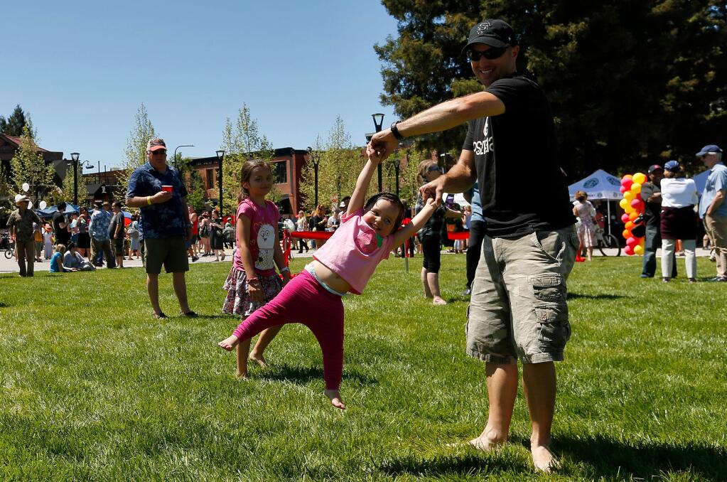 Brion Borba swings his youngest daughter around on the grass during the celebration of the reunified Old Courthouse Square in Santa Rosa on Saturday, April 29, 2017. (ALVIN JORNADA/ PD)