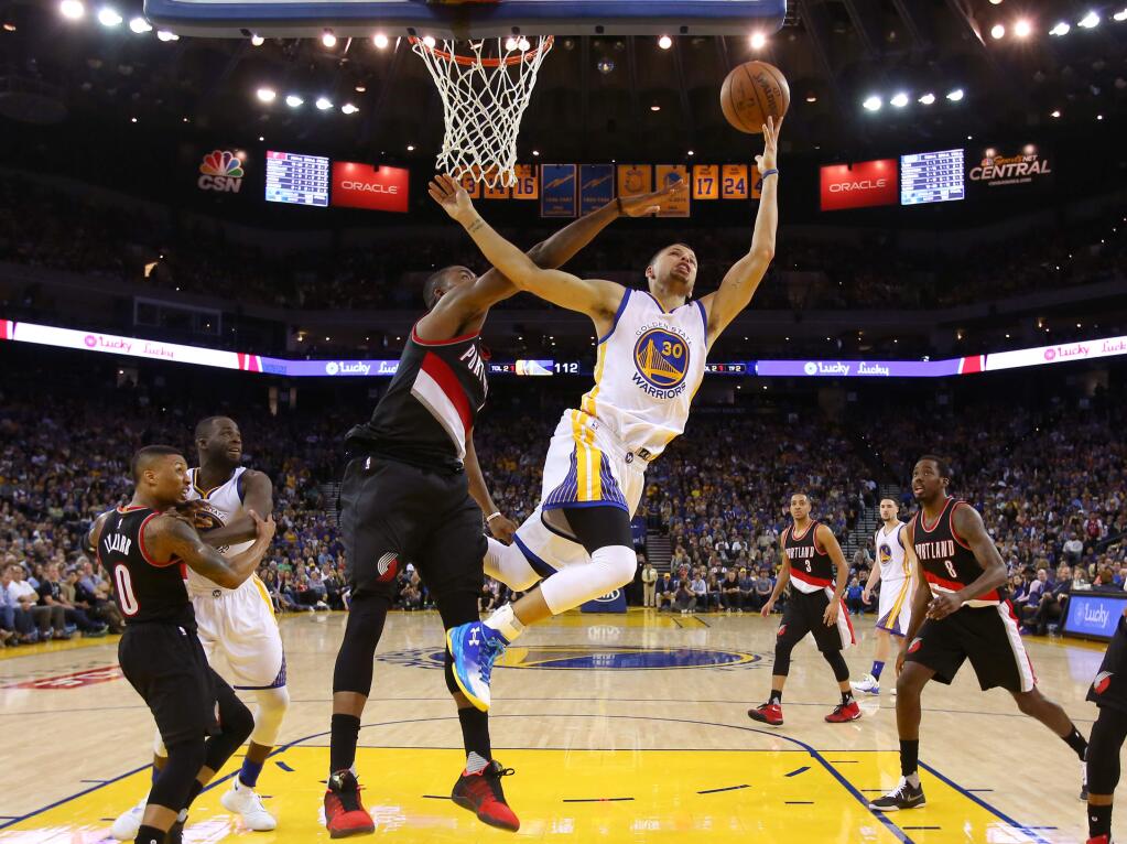 Golden State Warriors guard Stephen Curry drives to the basket against Portland Trailblazers forward Maurice Harkless, during their game in Oakland on Sunday, April 3, 2016. The Warriors defeated the Trailblazers 136-111. (Christopher Chung/ The Press Democrat)