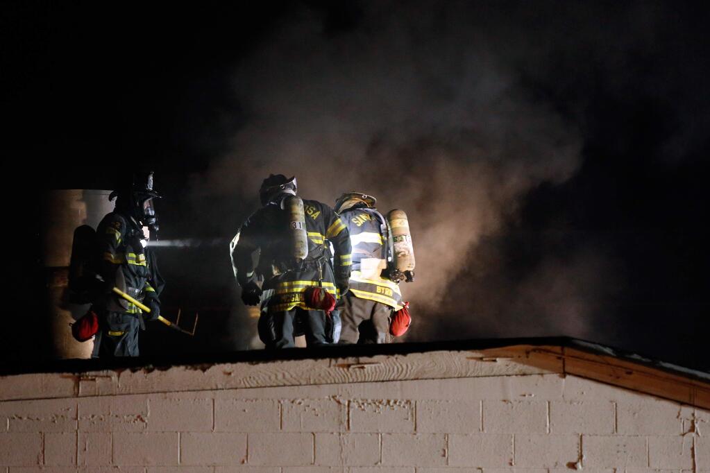 Santa Rosa firefighters cut a vent hole in the roof of a building during a two-alarm fire at John's Formica Shop in Santa Rosa, California, on Tuesday, November 29, 2016. (Alvin Jornada / The Press Democrat)