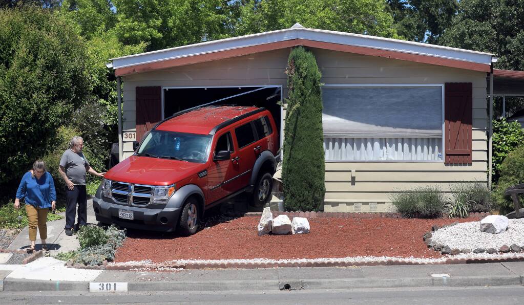 Lawrence Miller surveys damage to his vehicle with his daughter, Renée Clay, after he accidentally backed his SUV into a neighbor's home on Tuesday, May 28, 2019 in Santa Rosa. (KENT PORTER/ PD)