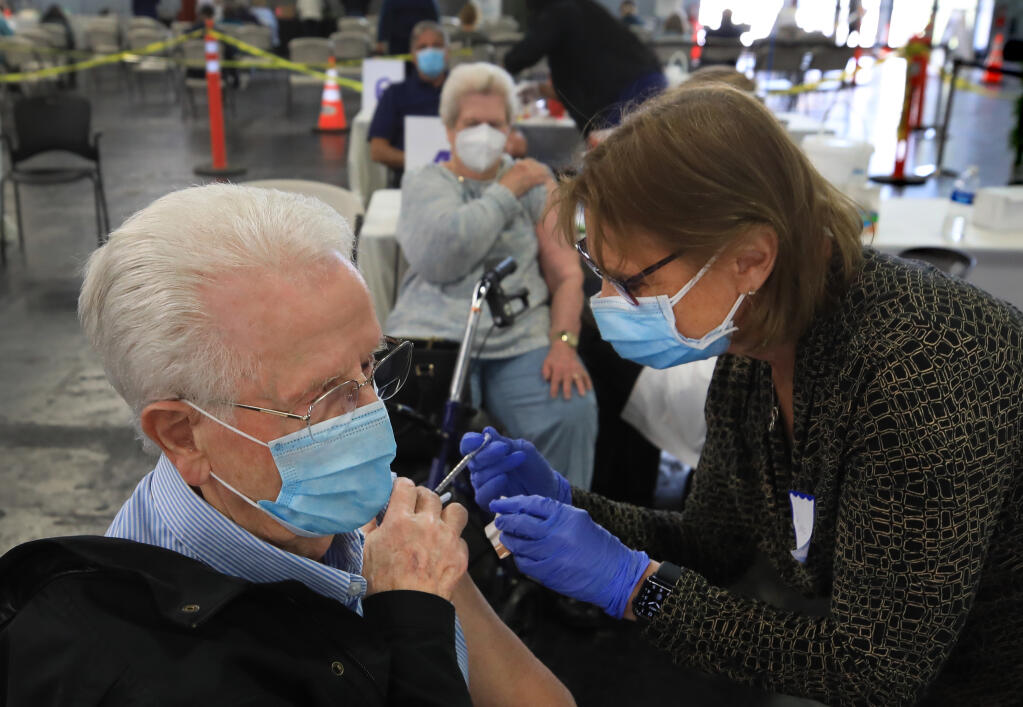 Evan, left, and his wife, Ardath Parry, middle background, receive their second Moderna vaccines, from RN Barbara Kohley, right, and  Dr. Loie Sauer, obscured,  during Sonoma County Medical Association's vaccine clinic at the Sonoma County Fairgrounds, Wednesday, March 3, 2021 in Santa Rosa.  (Kent Porter / The Press Democrat) 2021