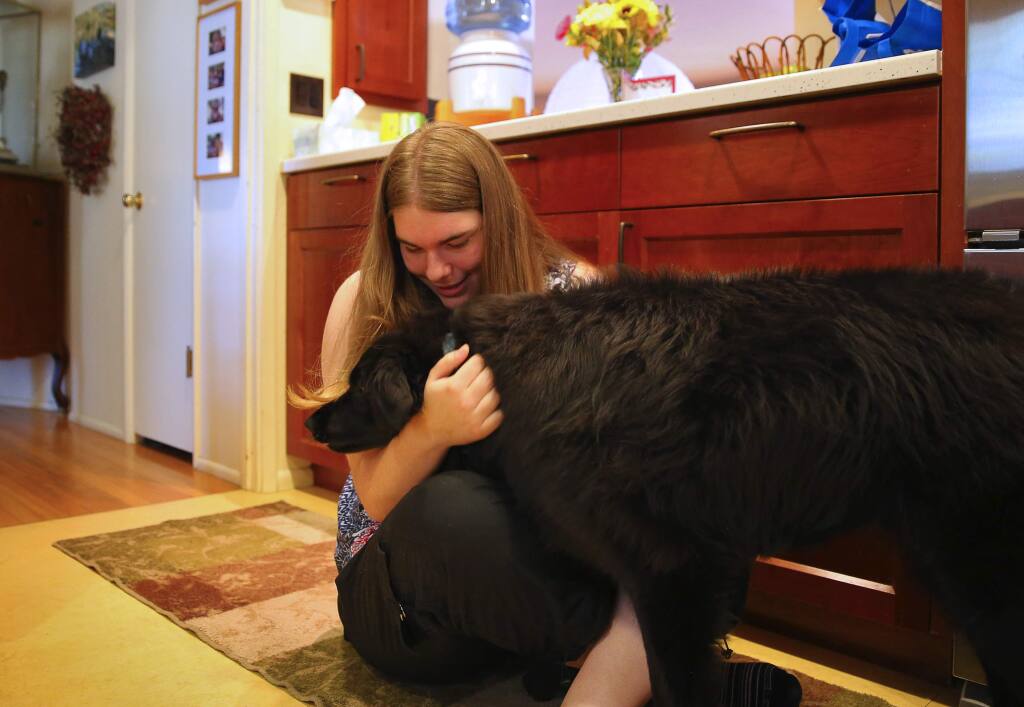 Claire Olney, 17, pets her dog, Bobbi, at her home in Santa Rosa, on Thursday, June 23, 2016. Olney has been diagnosed with Kleine-Levin syndrome, which causes her to sleep for 20 hours per day for a period of approximately six weeks. The episodes occur once or twice per year.(Christopher Chung/ The Press Democrat)