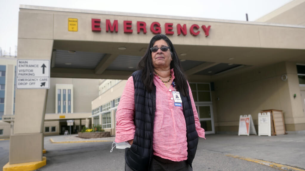Angelique Ramirez, chief medical officer at Foundation Health Partners in Fairbanks, poses for a photograph in front of the emergency entrance at Fairbanks Memorial Hospital on Tuesday, Sept. 21, 2021, in Fairbanks, Alaska. Fairbanks Memorial Hospital on Friday, Oct. 1, 2021, said it activated the Crisis Standards of Care policy because of a critical shortage of bed capacity, staffing and monoclonal antibody treatments, along with the inability to transfer patients to other facilities. (AP Photo/Rick Bowmer)