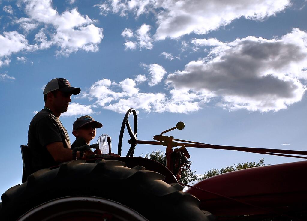 Jeff Vieira and his son Aiden, 5, drive a vintage tractor pulling the Lytton Springs 4-H float during the 70th annual Twilight Parade in Healdsburg, California, on Thursday, May 23, 2019. (Alvin Jornada / The Press Democrat)