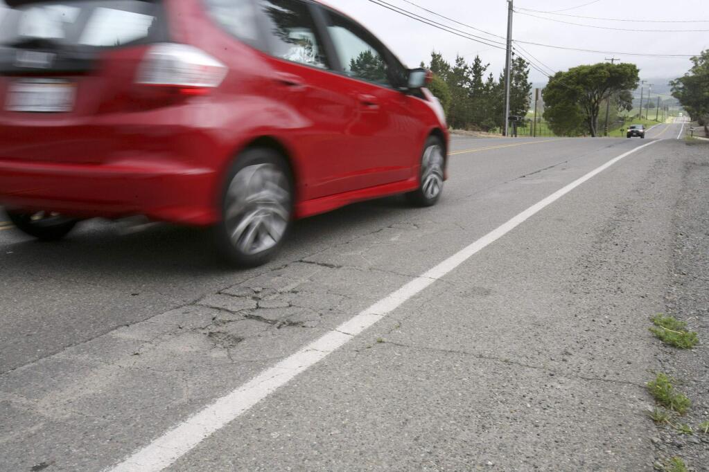 A car drives past cracked roadway of Corona Road which is a patchwork of repairs on Monday, March 23, 2015. (SCOTT MANCHESTER/ARGUS-COURIER STAFF)