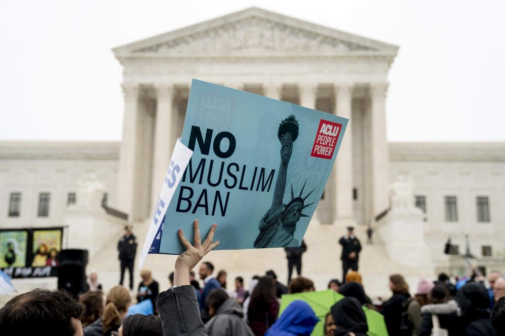 A person holds up a sign that reads 'No Muslim Ban' during an anti-Muslim ban rally as the Supreme Court hears arguments about wether President Donald Trump's ban on travelers from several mostly Muslim countries violates immigration law or the Constitution, Wednesday, April 25, 2018, in Washington. (AP Photo/Andrew Harnik)