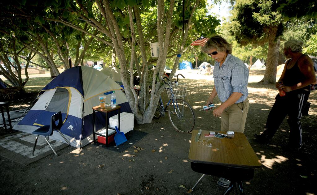 James Carver, left, cleans up his campsite in Cancer Survivors Park in downtown Santa Rosa, Tuesday, July 7, 2020.  (Kent Porter / The Press Democrat) 2020