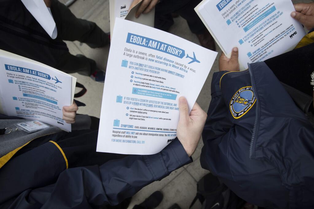 In this Oct. 24, 2014 file photo, members of the Brooklyn Borough President's office hand out fliers detailing the risks of Ebola outside The Gutter bowling alley in Brooklyn's Williamsburg neighborhood, in New York. (AP Photo/John Minchillo)