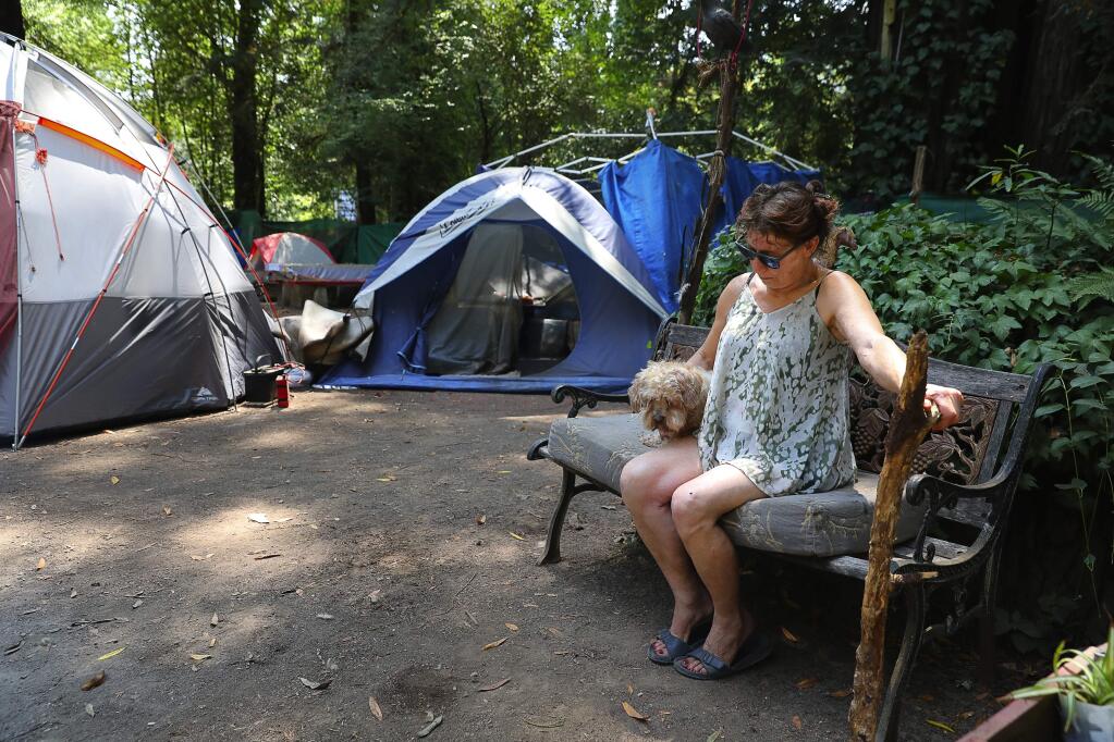 Deborah Johnson sits with her dog, Toya, at her campsite at the Faerie Ring Campground, in Guerneville on Wednesday, August 22, 2018. Johnson has lived at the campground for six months.(Christopher Chung/ The Press Democrat)