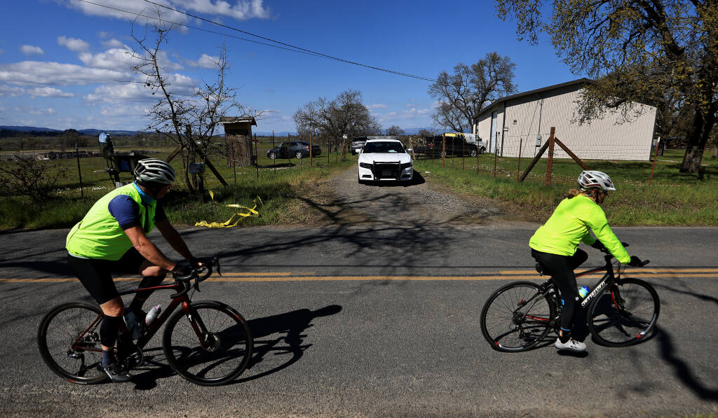 Bicyclists pass by the entrance to a shooting scene on Hall Road, Saturday, March 25, 2023 between Santa Rosa and Sebastopol. (Kent Porter / The Press Democrat file)