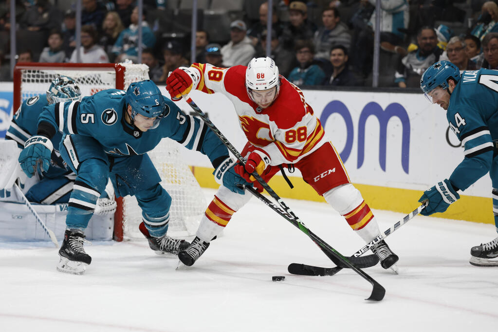 Sharks defensemen Matt Benning, left, and Marc-Edouard Vlasic battle for the puck against Calgary Flames left wing Andrew Mangiapane in the second period Sunday in San Jose (Josie Lepe / ASSOCIATED PRESS)