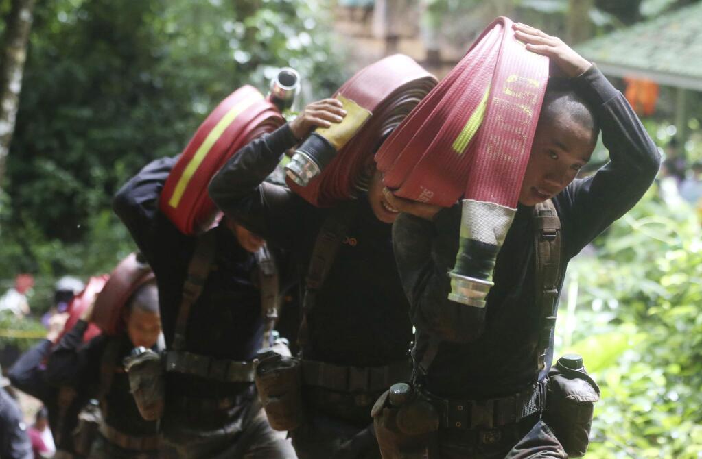 Thai soldiers bring hoses and additional water pumps to continue the search for 12 young soccer team members and their coach after going missing in Tham Luang Nang Non cave in Mae Sai, Chiang Rai province, northern Thailand Wednesday, June 27, 2018. Rain is continuing to fall and water levels keep rising inside a cave in northern Thailand, frustrating the search for the 12 boys and their soccer coach who have been missing since Saturday. (AP Photo/Sakchai Lalit)