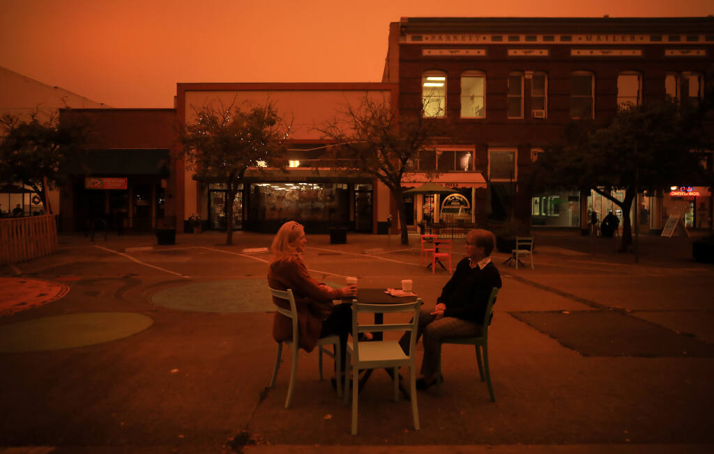 Friends, who requested not to have their names published, share some quiet time on Fourth Street in Santa Rosa, Wednesday, Sept. 9, 2020, as smoke from California wildfires fouls the air. (Kent Porter / The Press Democrat)