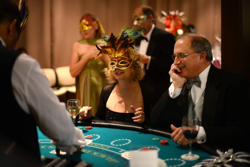 Kim McEachron (left) and John Evans at the blackjack table during the 18th annual 4-A-Child Masquerade Ball, a benefit of the California Parent Institute, held at the DeTurk Round Barn in Santa Rosa on Saturday, Nov. 8, 2014. (ERIK CASTRO/ FOR THE PD)