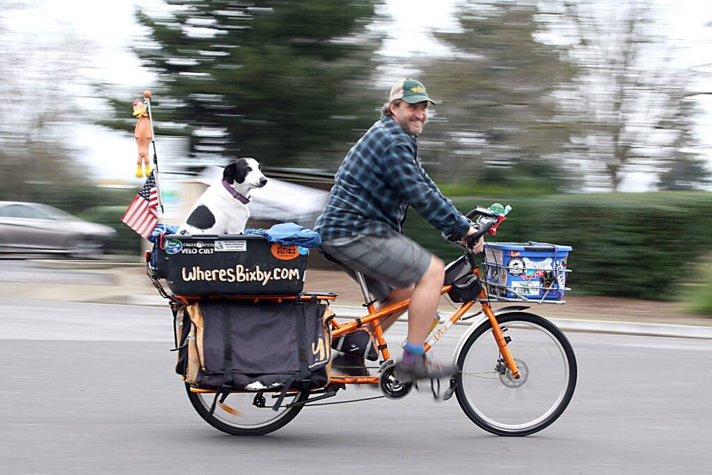 Mike Minnick and his dog Bixby who have travled 7,500 miles by bike to Petaluma by way of Maine, Florida, Seattle and all points in between to support animal shelters, rides in Petaluma on Tuesday December 9, 2014. (SCOTT MANCHESTER/ARGUS-COURIER STAFF)
