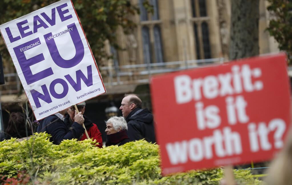 Pro and anti Brexit protesters hold placards as they vie for media attention near Parliament in London, Friday, Nov. 16, 2018. Britain's Prime Minister May still faces the threat of a no-confidence vote, after several Conservative Party lawmakers said they had written letters asking for one. (AP Photo/Alastair Grant)