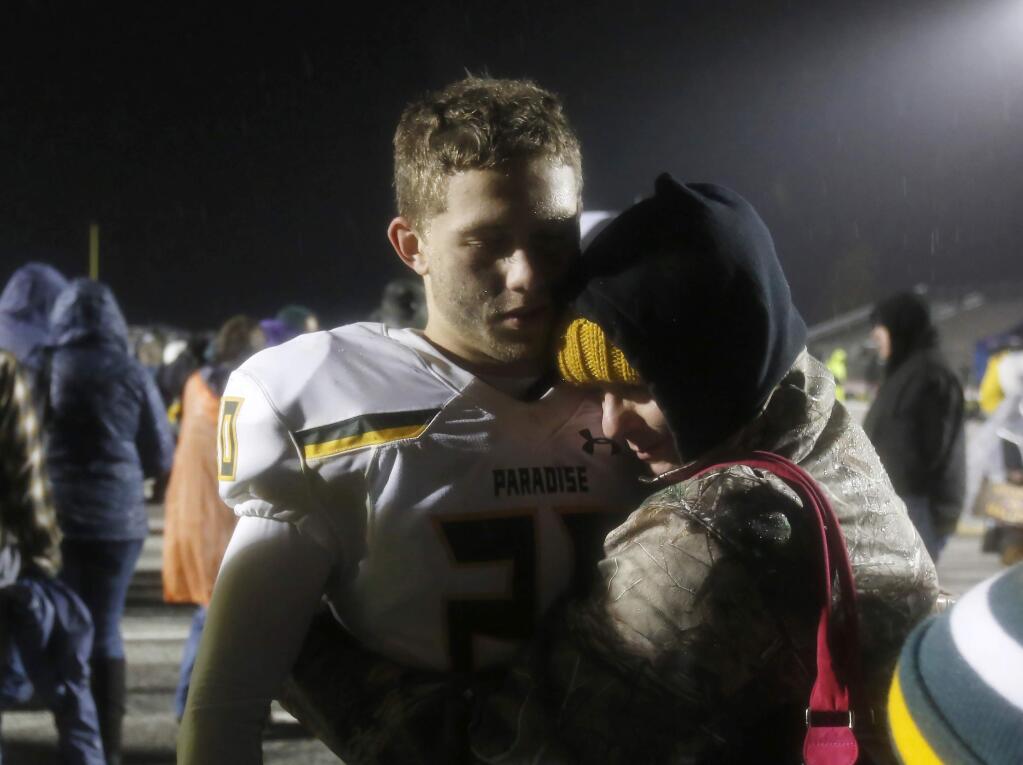 Paradise running back Lukas Hartley is hugged by his mother, Laura Nelson, after Paradise's 20-7 loss to Sutter Union in the Northern Section Division III high school football championship game Saturday, Nov. 30, 2019, in Yuba City, Calif. Paradise had an undefeated season and made it to the section championship game a year after the deadliest wildfire in California history that killed dozens and destroyed nearly 19,000 buildings including the homes of most of the players. (AP Photo/Rich Pedroncelli)
