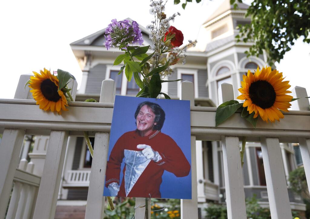 A photo of the late actor Robin Williams as Mork from Ork hangs with flowers left by people paying their respects, in Boulder, Colo., Monday Aug. 11, 2014, at the home where his hit 80's TV series 'Mork & Mindy', was set. (AP Photo/Brennan Linsley)
