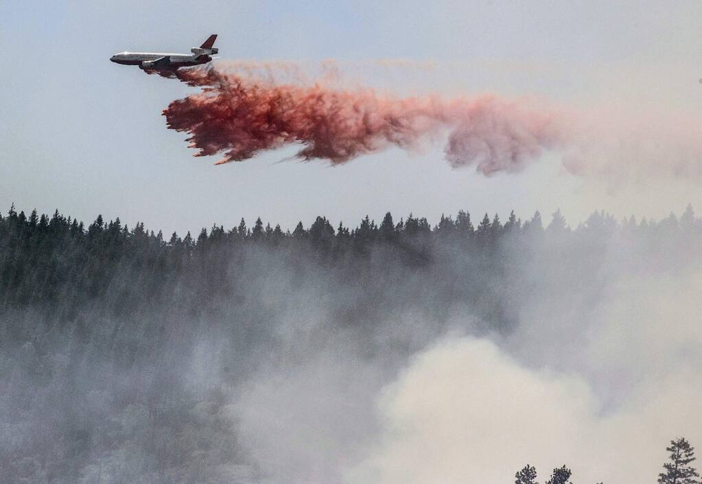 A plane drops fire retardant as firefighters battle a blaze in El Portal, near Yosemite National Park, on Tuesday, July 29, 2014. (AP Photo/Al Golub)