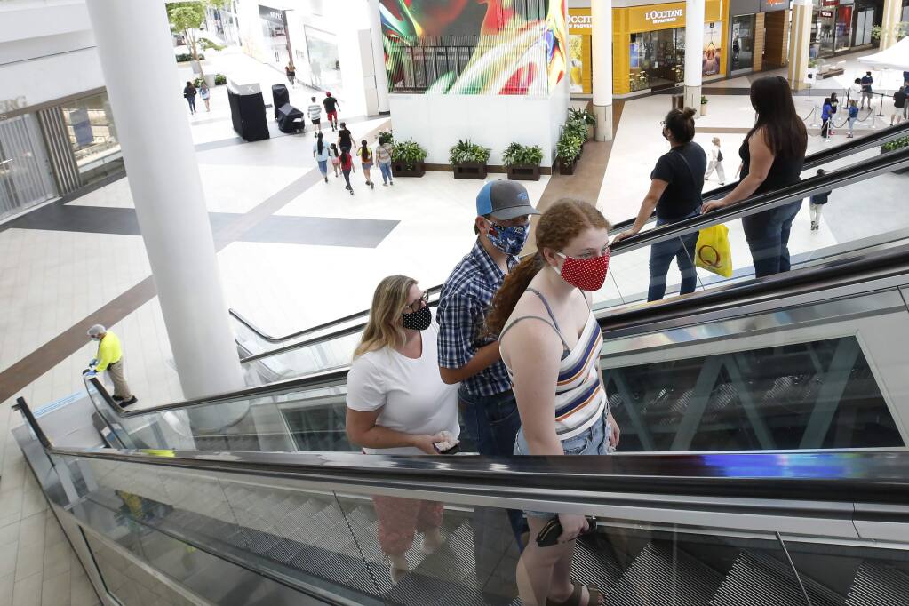 People wearing face masks take an escalator to the second floor of the Arden Fair Mall in Sacramento, Calif., Friday, May 29, 2020. Arden Fair reopened Friday since closing in March due to the coronavirus pandemic. (AP Photo/Rich Pedroncelli)