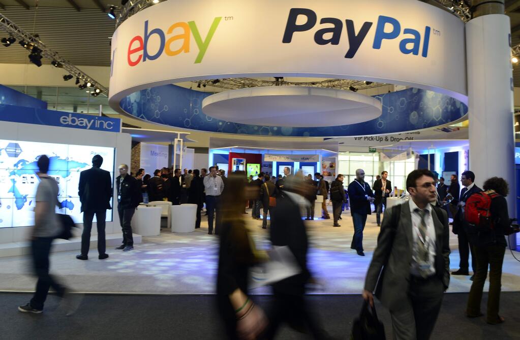FILE - In this Wednesday, Feb. 27, 2013, file photo, attendees walk in front of an EBay and PayPal display area at the Mobile World Congress, the world's largest mobile phone trade show, in Barcelona, Spain. PayPal is splitting from EBay Inc. and will become a separate and publicly traded company during the second half of 2015. (AP Photo/Manu Fernandez, File)