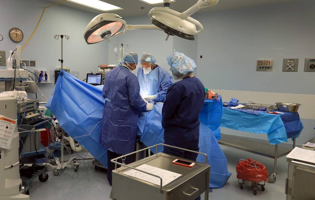 Surgeon David Kitts, scrub technician Jimmy May and circulating room nurse, Deanna Rickard, perform and assist in a surgery, Friday, April 13, 2018 at Sonoma West Medical Center in Sebastopol. (Kent Porter / The Press Democrat) 2018